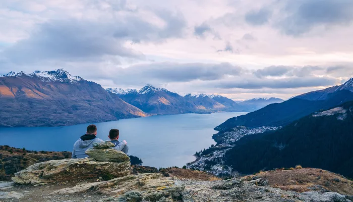 Two people sitting on Queenstown Hill overlooking Lake Wakatipu and the Southern Alps