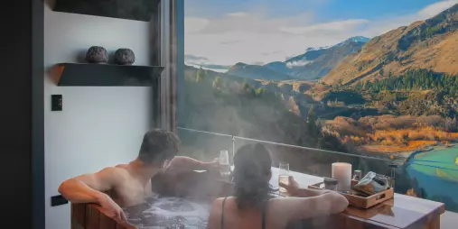 Couple relaxing in a hot pool with mountain views at Onsen Hot Pools in Queenstown