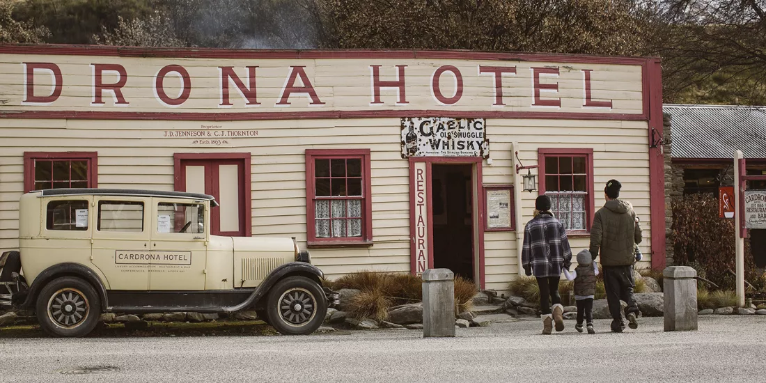A family walks toward the historic Cardrona Hotel in Wanaka