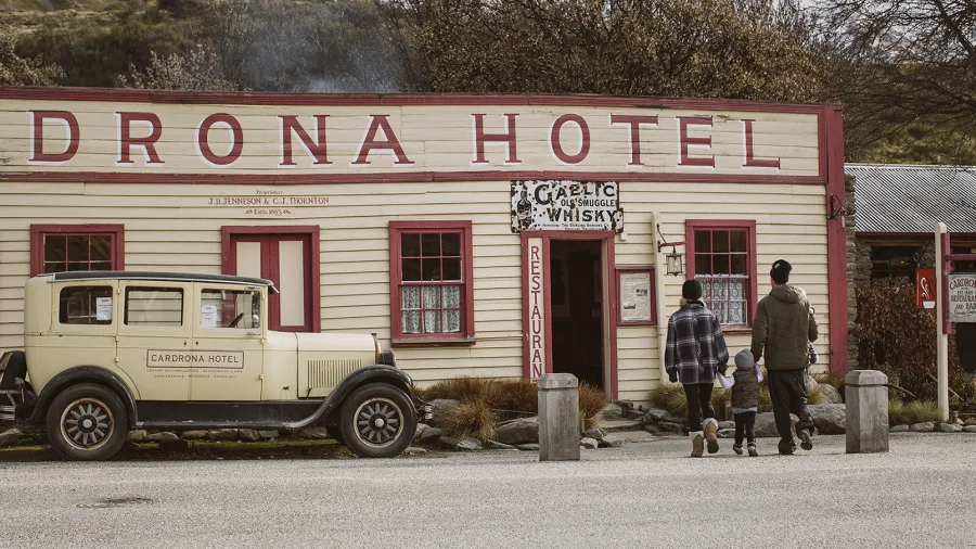 A family walks toward the historic Cardrona Hotel in Wanaka