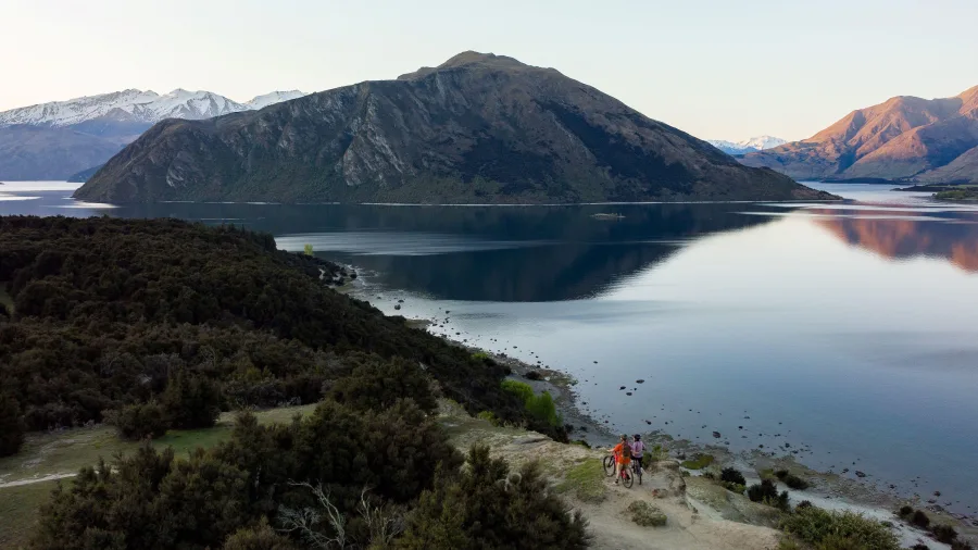 Two cyclists with e-bikes overlooking Lake Wānaka from Sticky Forest
