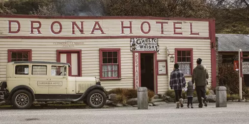 A family walks toward the historic Cardrona Hotel in Wanaka