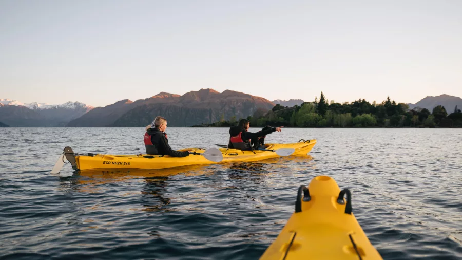 People kayaking on Lake Wānaka near Ruby Island at sunset