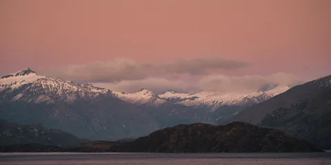 Snow-covered mountains of Aspiring National Park at sunset seen from Lake Wānaka