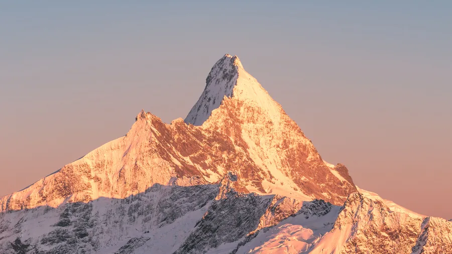 Sunlit peak of Mt Aspiring covered in snow and surrounded by glaciers