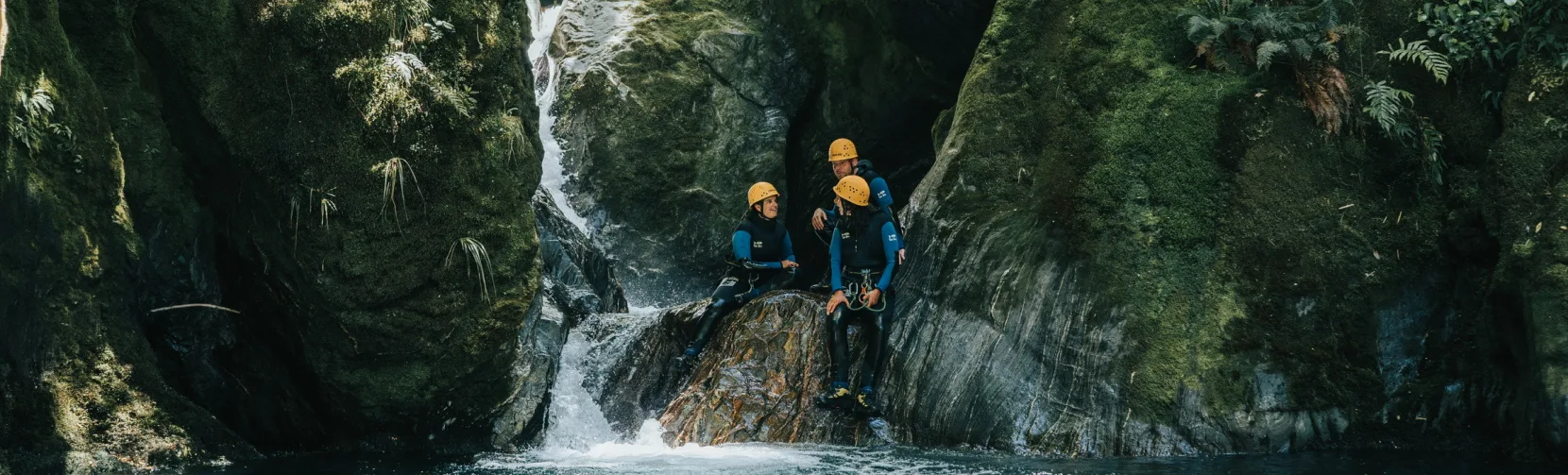 Group of canyoners preparing to descend into a turquoise pool on the Mt Aspiring adventure.