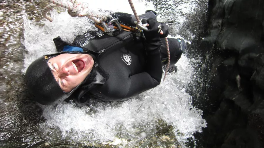 Excited canyoner mid-abseil through a waterfall in Niger Stream canyon near Wānaka.