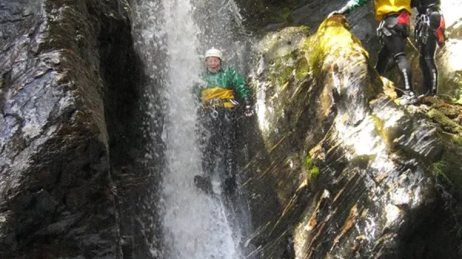 Canyon guide supporting a participant through a waterfall rappel in Wai Rata Canyon.