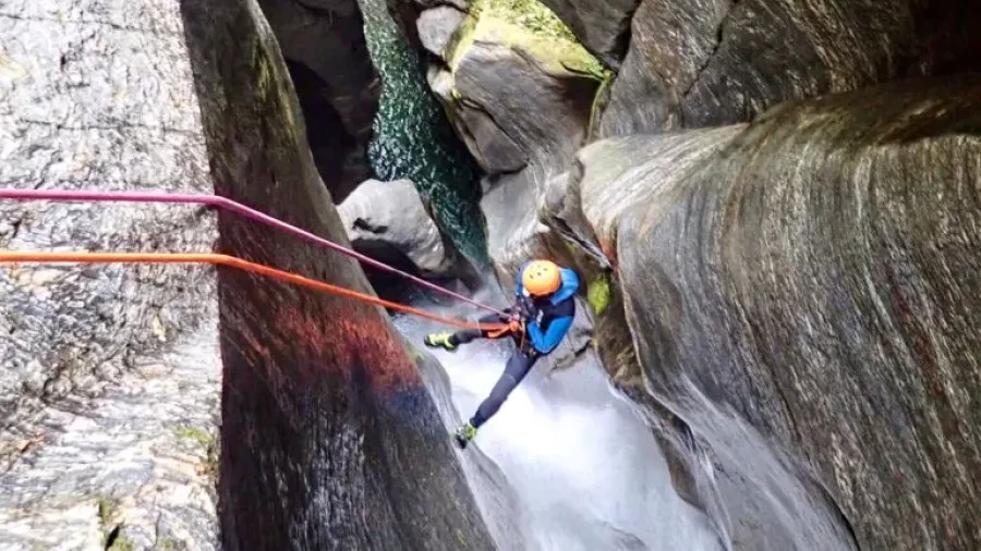 Canyoner abseiling down a narrow schist canyon in Imp Grotto near Wānaka.