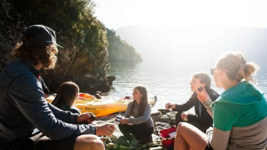 Group enjoying a lakeside snack break during the Tiki Guided Kayak Tour on Lake Wānaka
