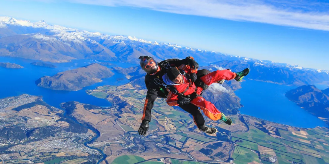 Skydiver freefalling above Lake Wanaka with alpine and lake landscape in full view