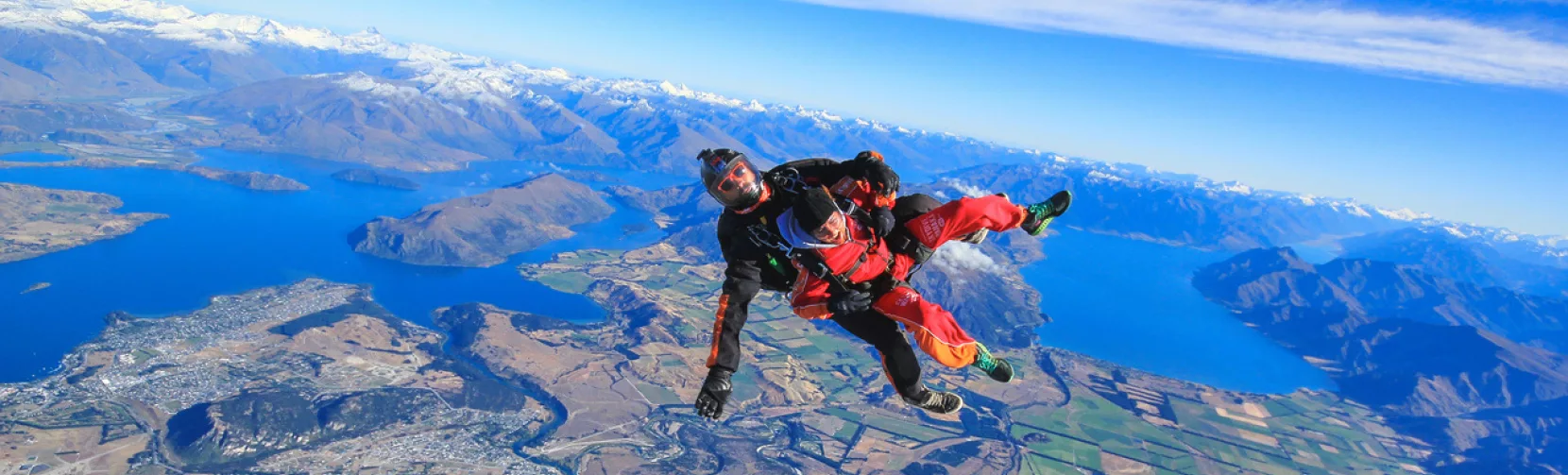 Skydiver freefalling above Lake Wanaka with alpine and lake landscape in full view