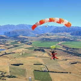Tandem skydivers descending with parachute open over Central Otago near Wanaka