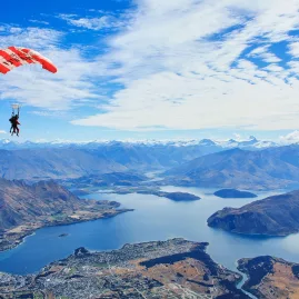 Skydiver descending over Lake Wanaka with the town and mountains below