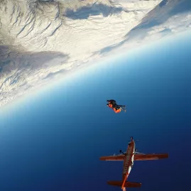 Skydiver falling with dramatic upside-down perspective above Wanaka landscape