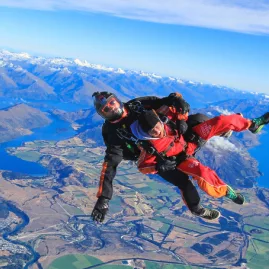 Skydiver freefalling above Lake Wanaka with alpine and lake landscape in full view