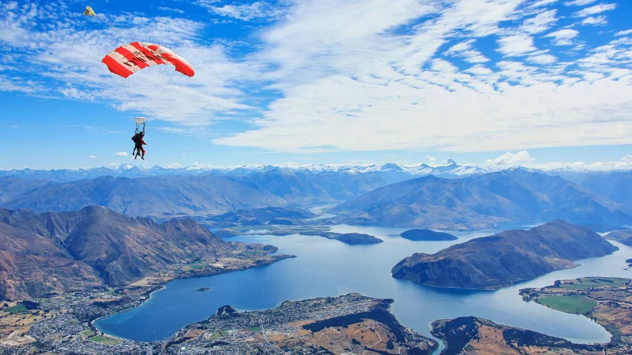 Skydiver descending over Lake Wanaka with the town and mountains below
