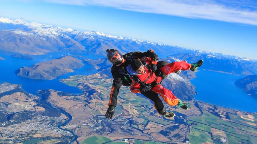 Skydiver freefalling above Lake Wanaka with alpine and lake landscape in full view