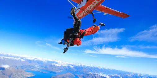 Skydiver jumping from a Skydive Wanaka aircraft with Lake Wanaka in the background