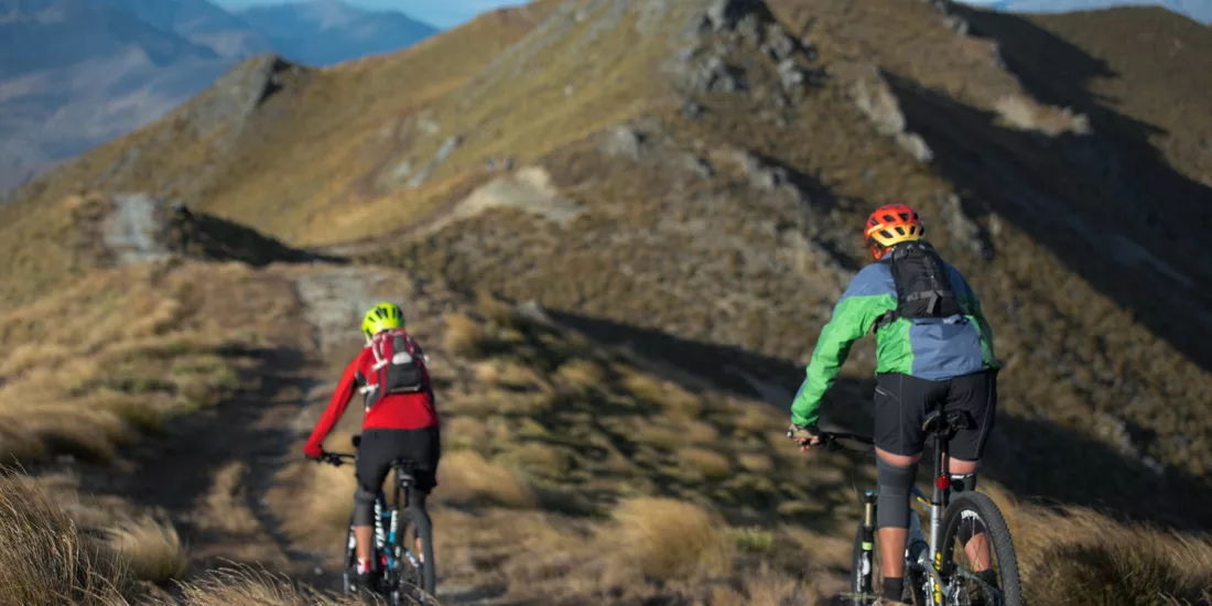 Mountain bikers cycling along a rugged high-country ridge near Cromwell