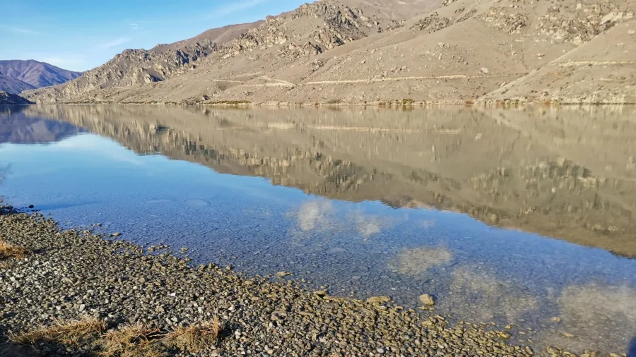 Clear water and mountain reflections on the Lake Dunstan shoreline