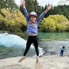 Child jumping for joy beside the Hawea River
