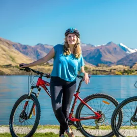 Two cyclists posing by Lake Wanaka after completing the trail