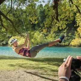 Woman on rope swing over Hawea River during bike ride