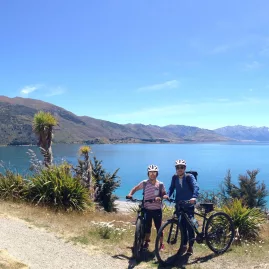 Two cyclists overlooking Lake Hawea with mountains in background