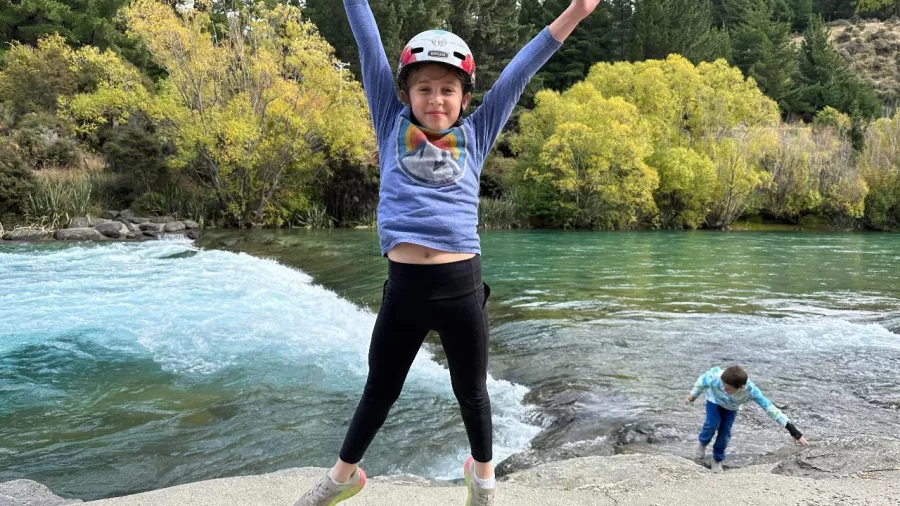 Child jumping for joy beside the Hawea River