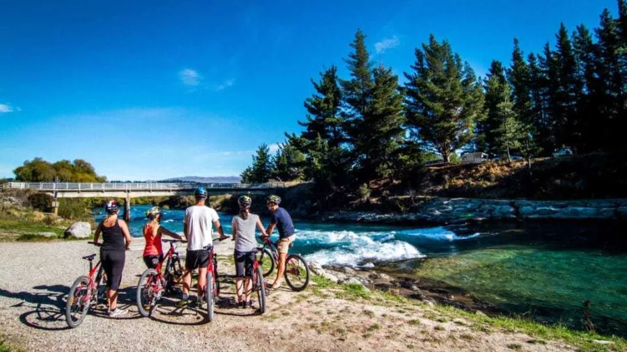 Cycling group stopped beside Hawea River Rapids near the start of the trail