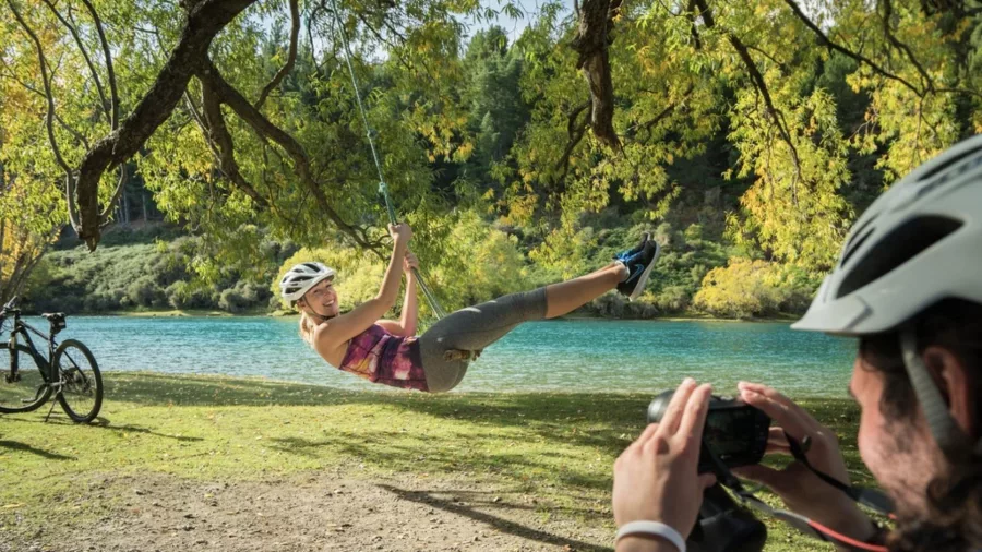 Woman on rope swing over Hawea River during bike ride