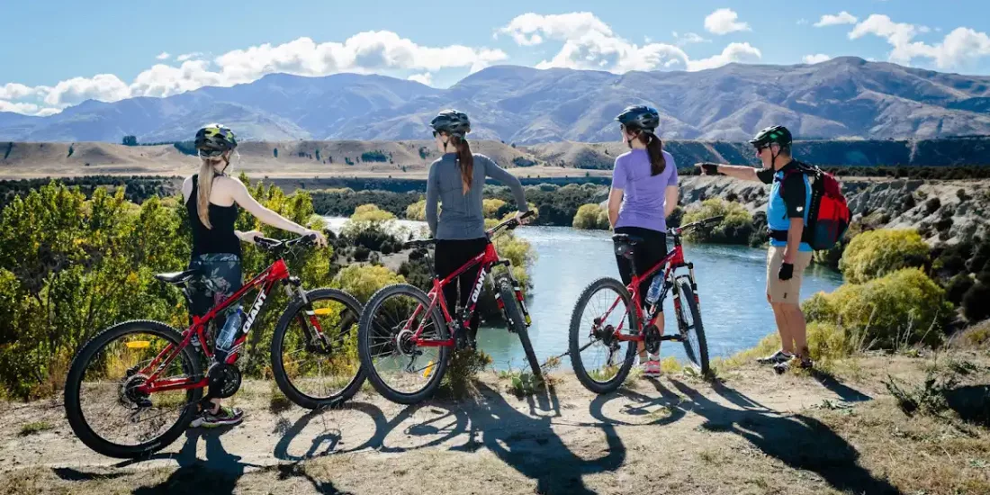 Cyclists enjoying a scenic lookout over the Upper Clutha River on the Albert Town to Wanaka bike trail.