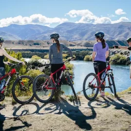 Cyclists enjoying a scenic lookout over the Upper Clutha River on the Albert Town to Wanaka bike trail.