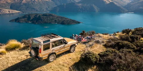 4WD parked on a hill with group enjoying panoramic views of Lake Wanaka and Stevenson’s Island.