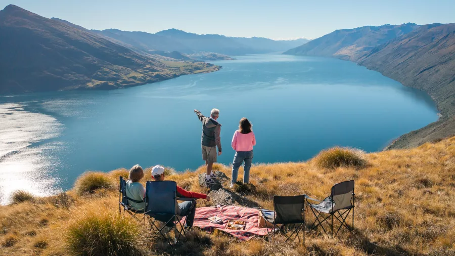 A group having a picnic on a ridge with panoramic views over Lake Wanaka.