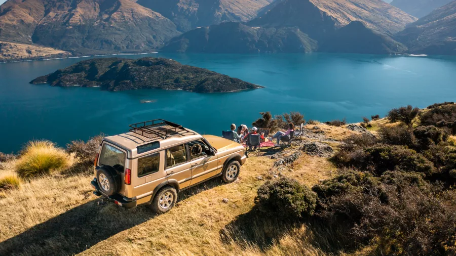 4WD parked on a hill with group enjoying panoramic views of Lake Wanaka and Stevenson’s Island.