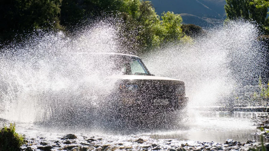 A Land Rover splashing through a shallow river crossing during a Wanaka 4WD tour.