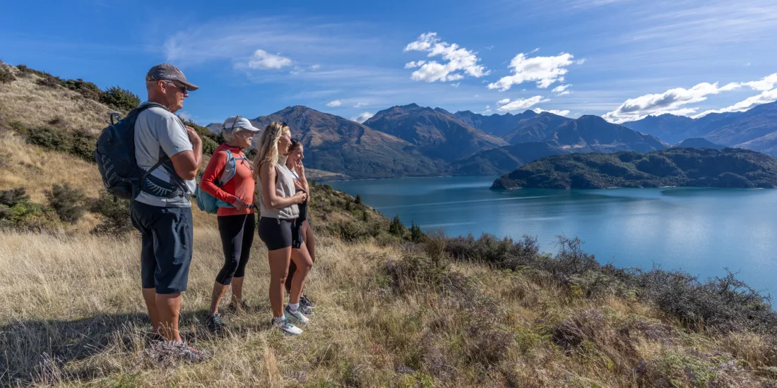 Family standing on hillside admiring Lake Wānaka view