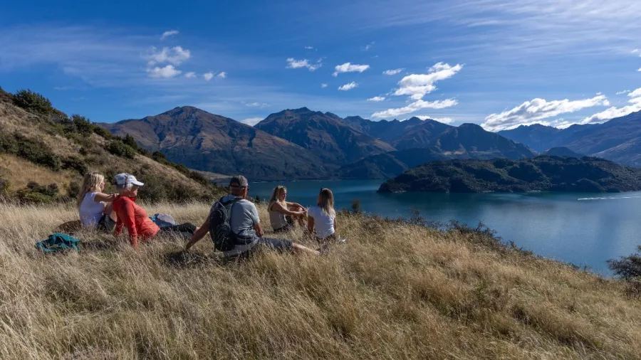 Family sitting on ground admiring lake and mountain views