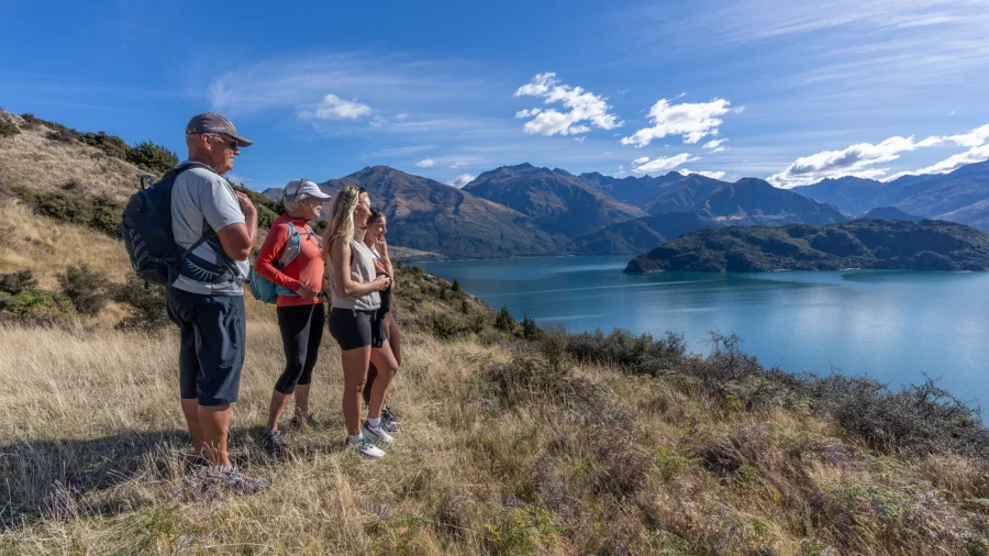 Family standing on hillside admiring Lake Wānaka view