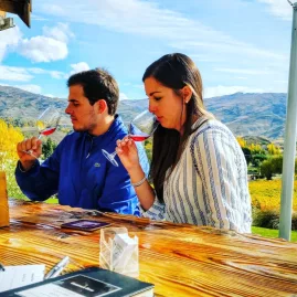 Couple enjoying a wine tasting with panoramic vineyard views in Central Otago during a private wine tour.