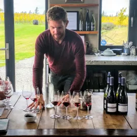 Winemaker presenting a selection of Pinot Noir during a wine tasting at a Central Otago vineyard.