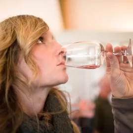 A woman enjoys a wine tasting indoors at a cellar door in Wanaka.