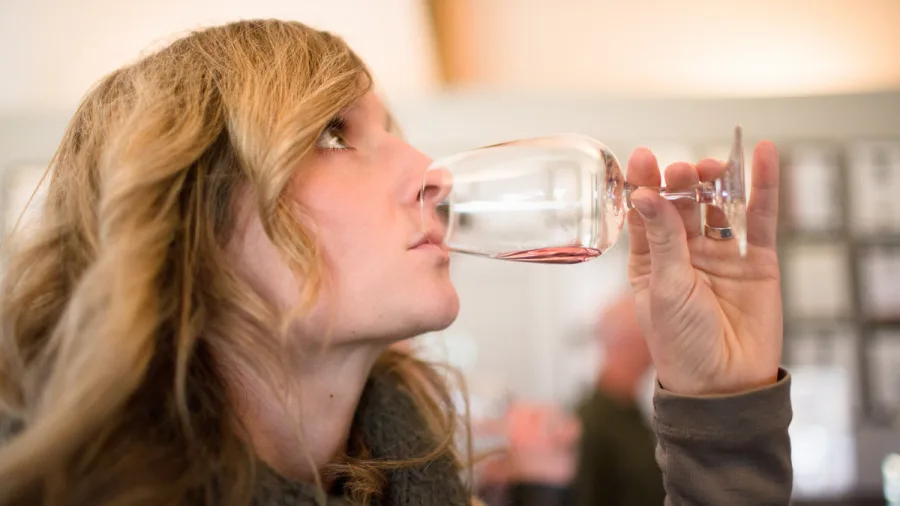 A woman enjoys a wine tasting indoors at a cellar door in Wanaka.