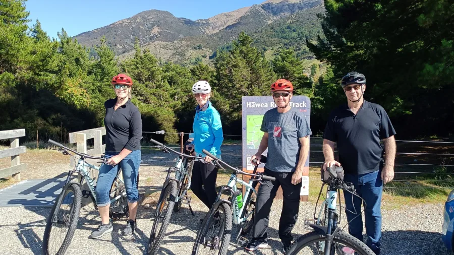 Family posing with bikes at the start of the Hawea River Track near Wanaka.