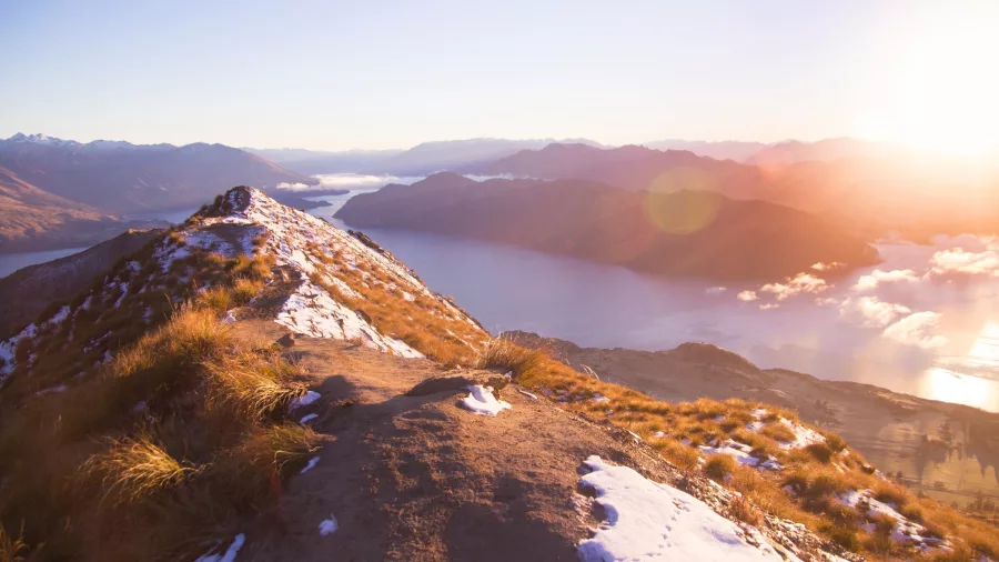 Roys Peak track summit at sunrise with views over Lake Wanaka and the Southern Alps in New Zealand