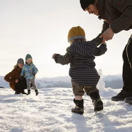 Family enjoying snow play at Cardrona Alpine Resort with children and toddlers in a winter setting