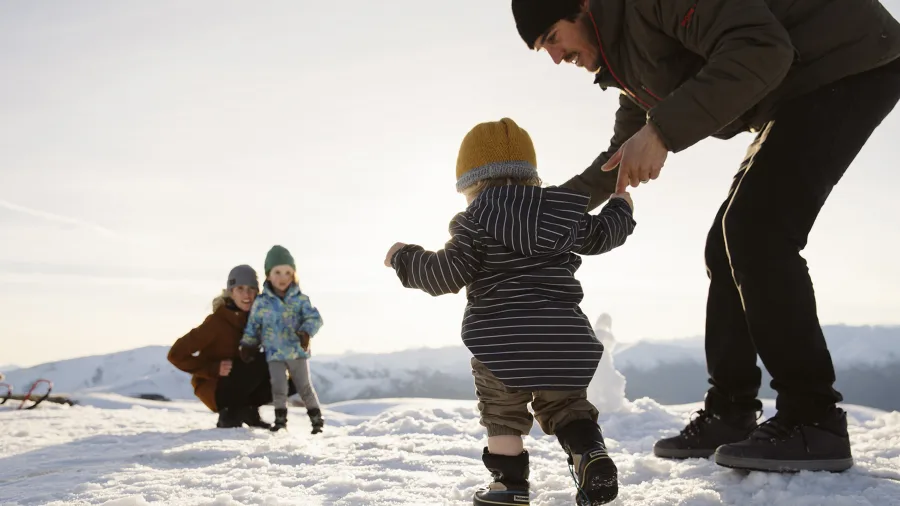 Family enjoying snow play at Cardrona Alpine Resort with children and toddlers in a winter setting
