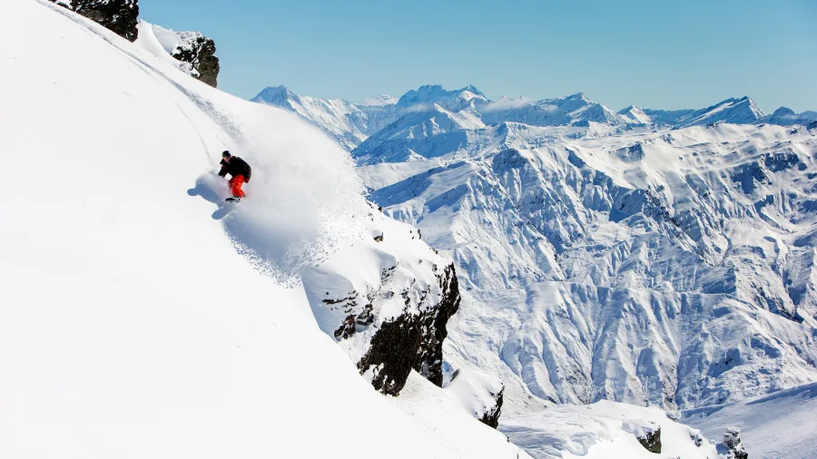 Snowboarder riding down steep terrain at Cardrona Alpine Resort, Wanaka